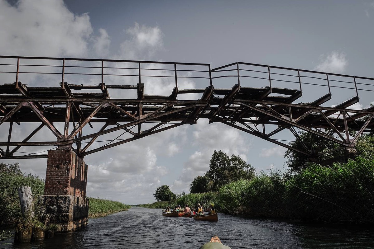 Canoes passing under old brige wrecks in Wilhelm canal, Klaipeda, Lithuania