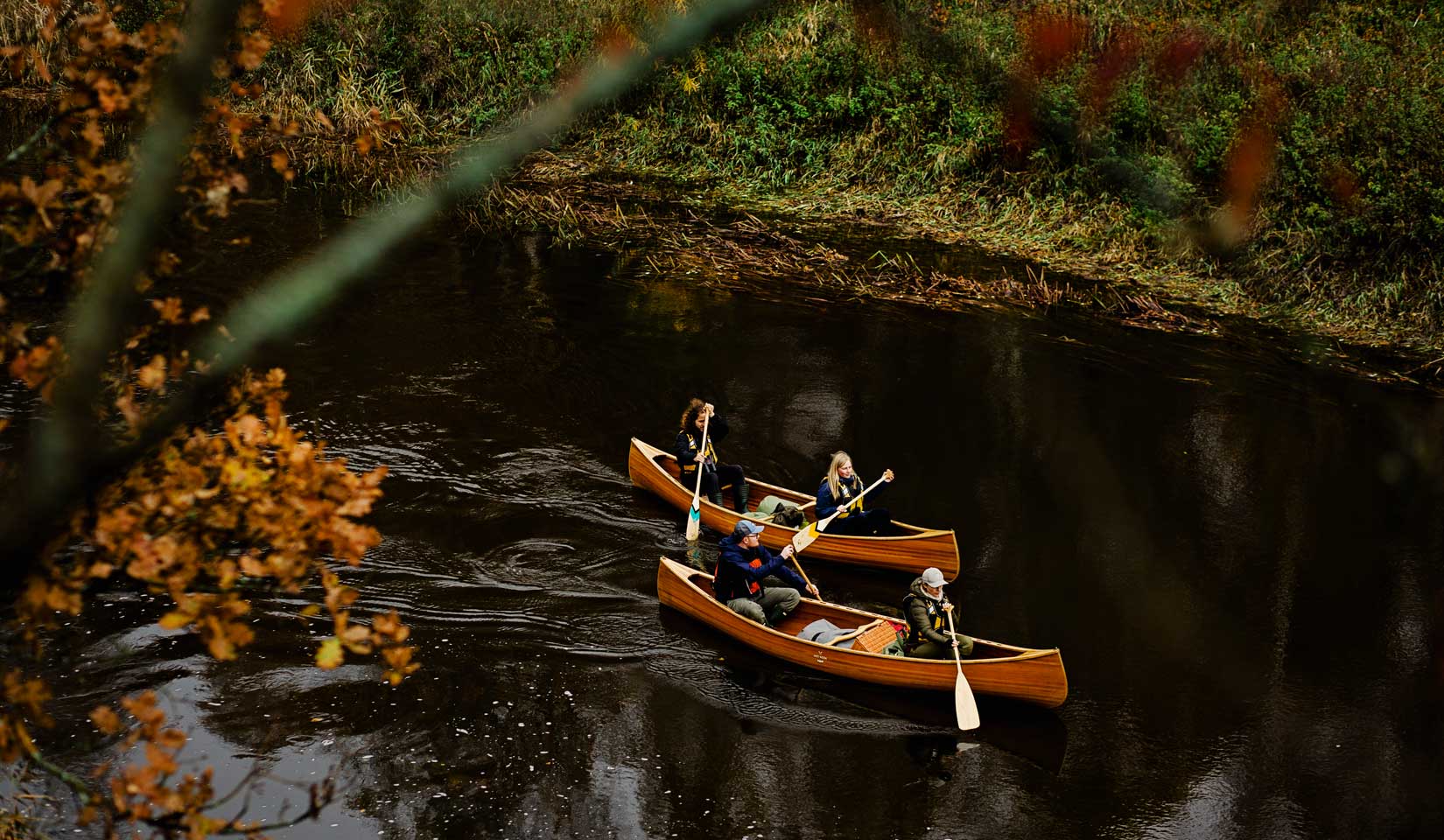 Medinės kedro kanojos leidžiasi upe